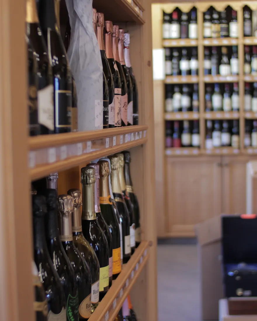 Scaffali di vini e bollicine nell’Enoteca Malanotti a Croviana, Val di Sole